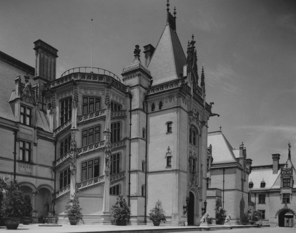 a black and white photograph of a large mansion with pointy rooftops and swirling staircases