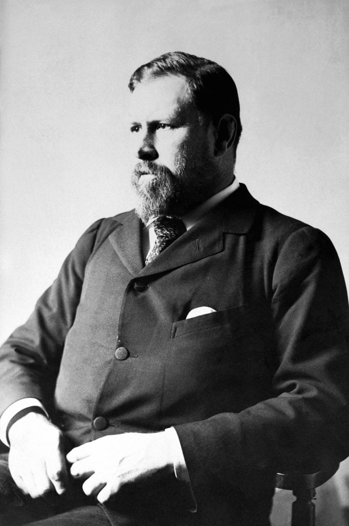 A bearded man, author Bram Stoker, is seated in a black suit