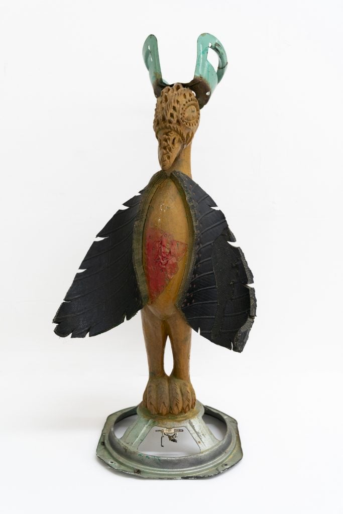 A sculpture of a birdlike figure made with wood, rubber tires, and found pieces of metal