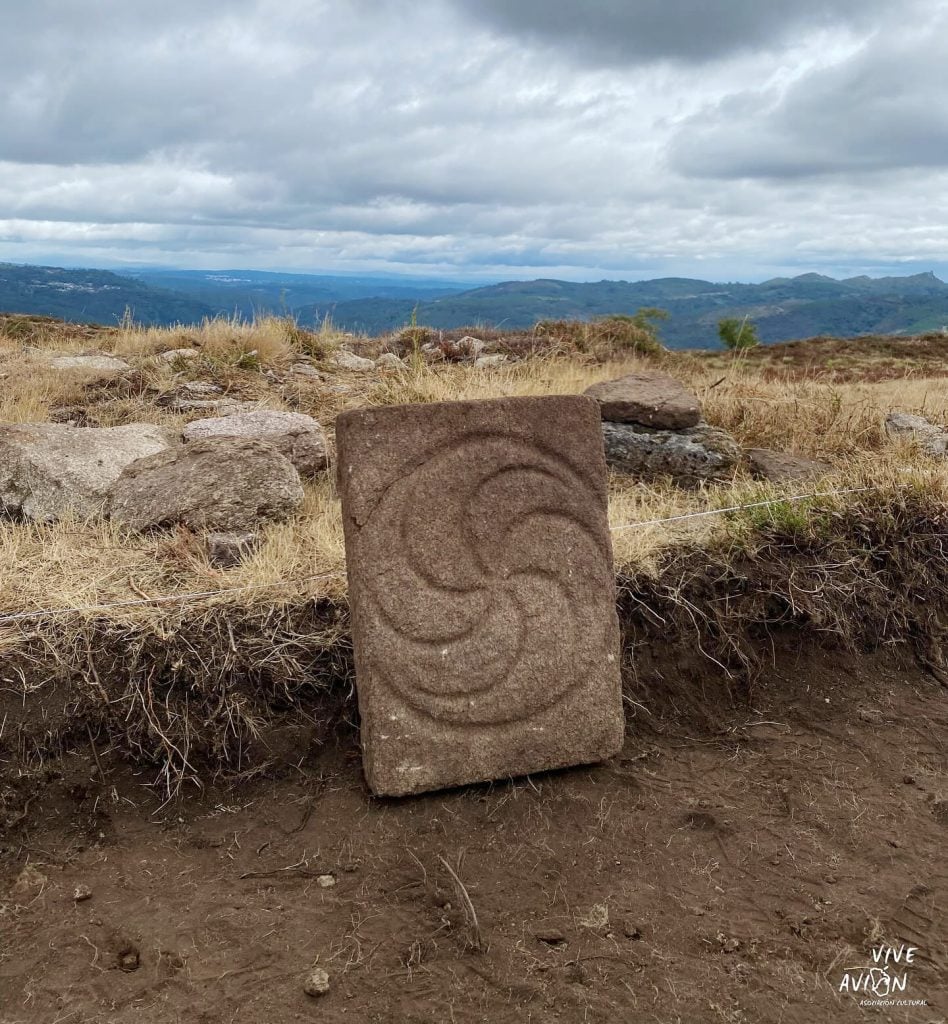 A stone slab with a circular carving sitting on a dirt path