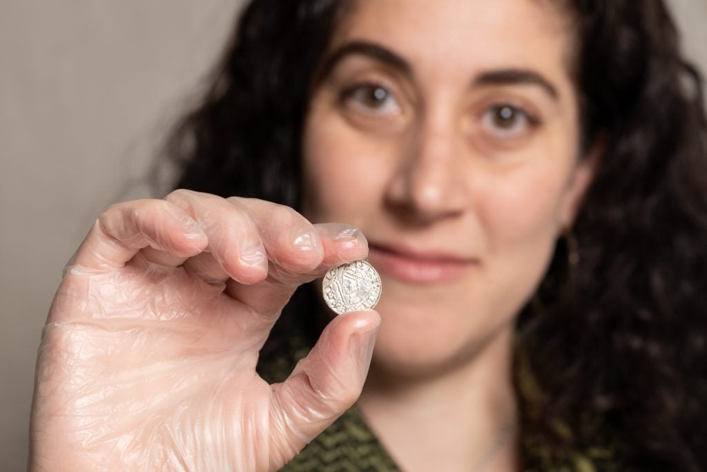 A woman holding up an ancient coin