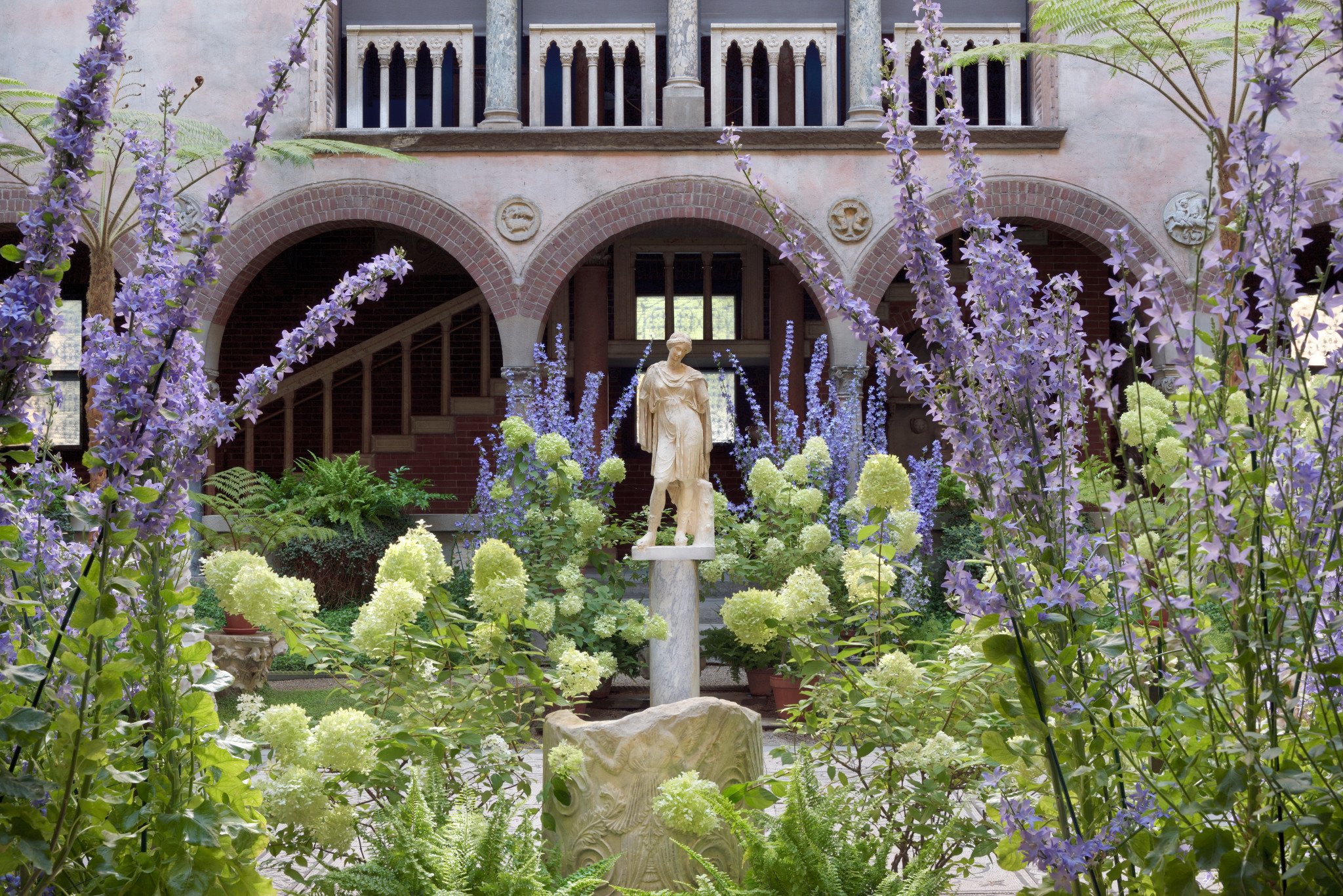 Flowering plants, a sculpture, and a beautiful interior courtyard in an antique style