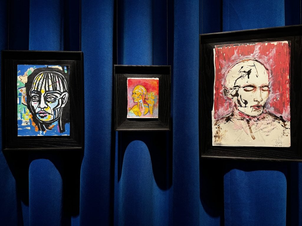 Three paintings by Johnny Depp of a mysterious figure hanging in a gallery