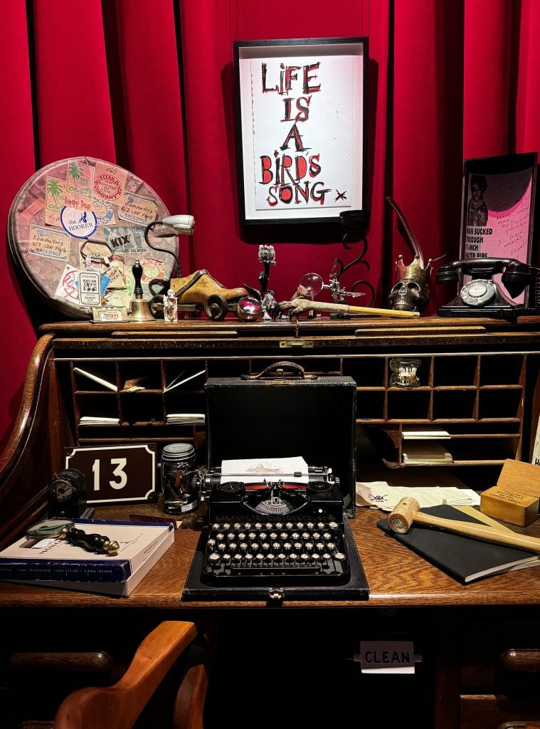 A vintage writing table with an old typewriter and other knickknacks on it