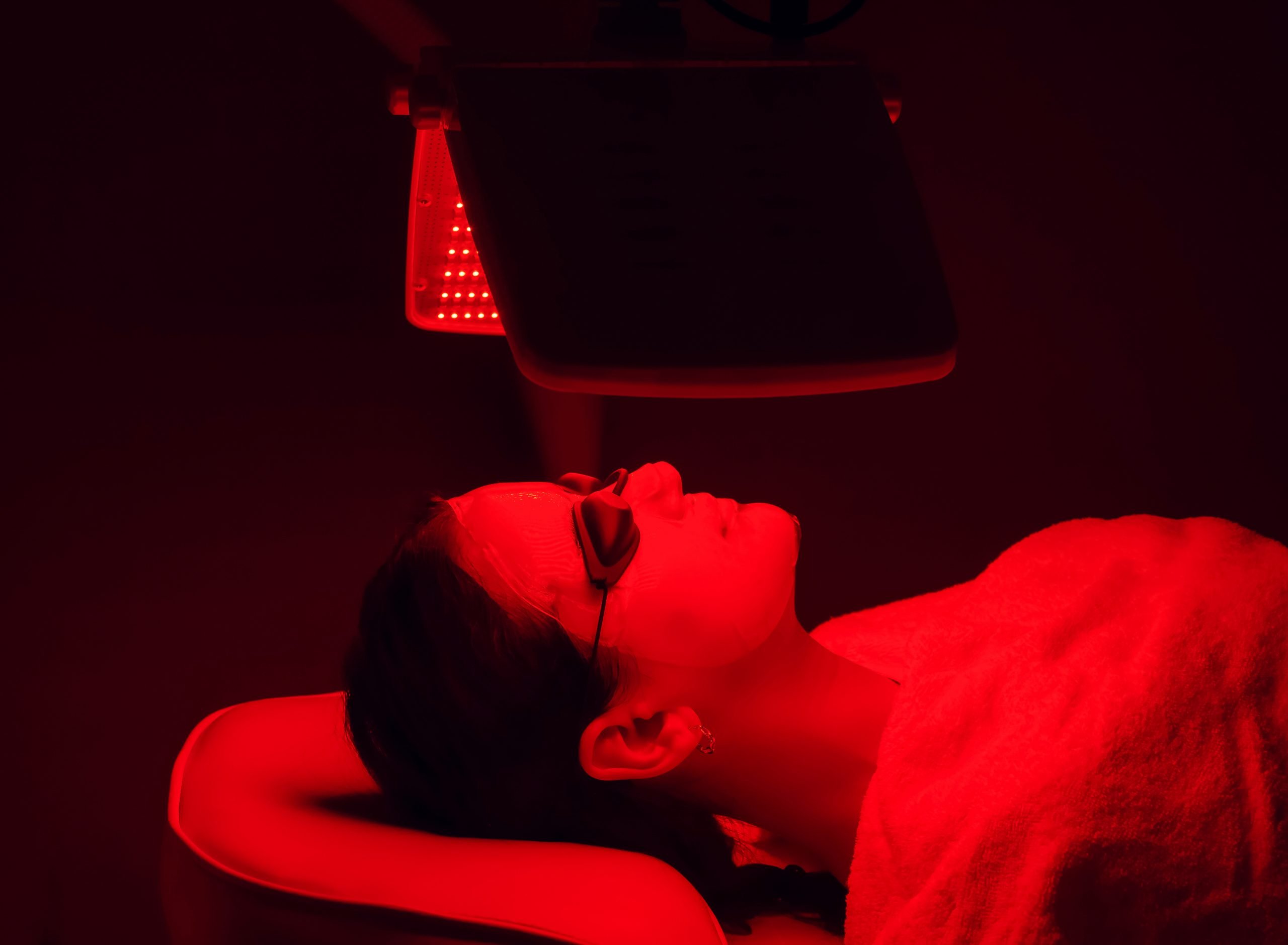 a woman wearing goggles sits under an infrared light