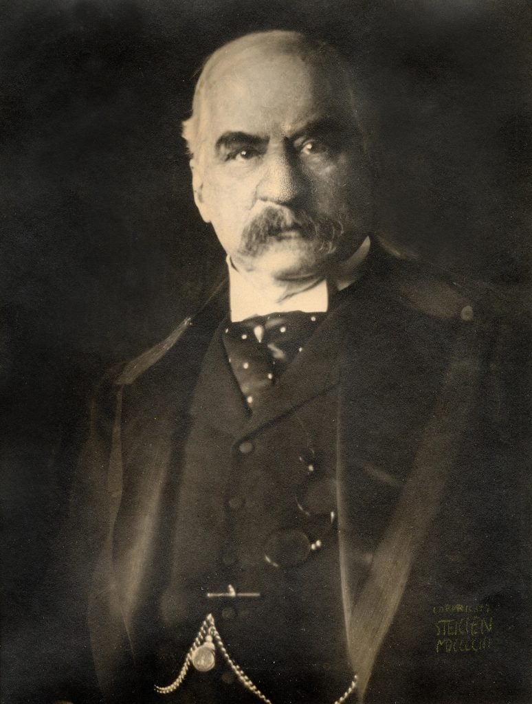 Black and white portrait of J. Pierpont Morgan wearing a black three-piece suit and a mustache against a black background, included in Artnet's Important Photographs sale.