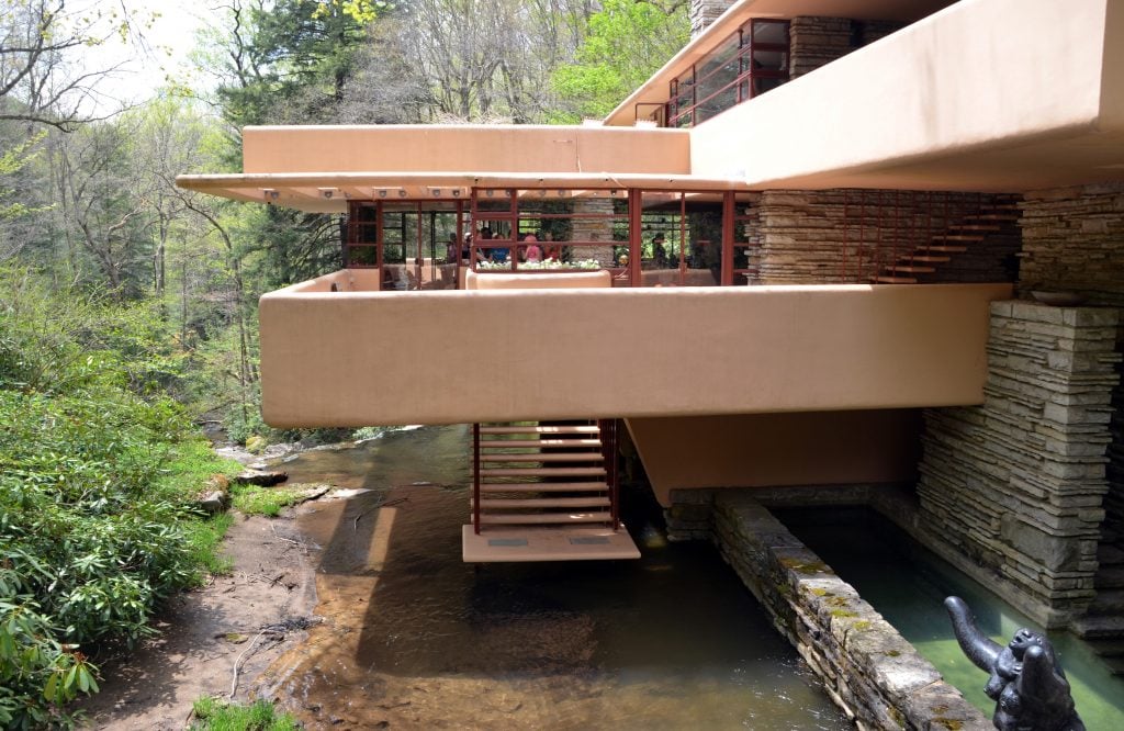 A photo showing Fallingwater, a house with a series of terraces and a staircase leading to a pool