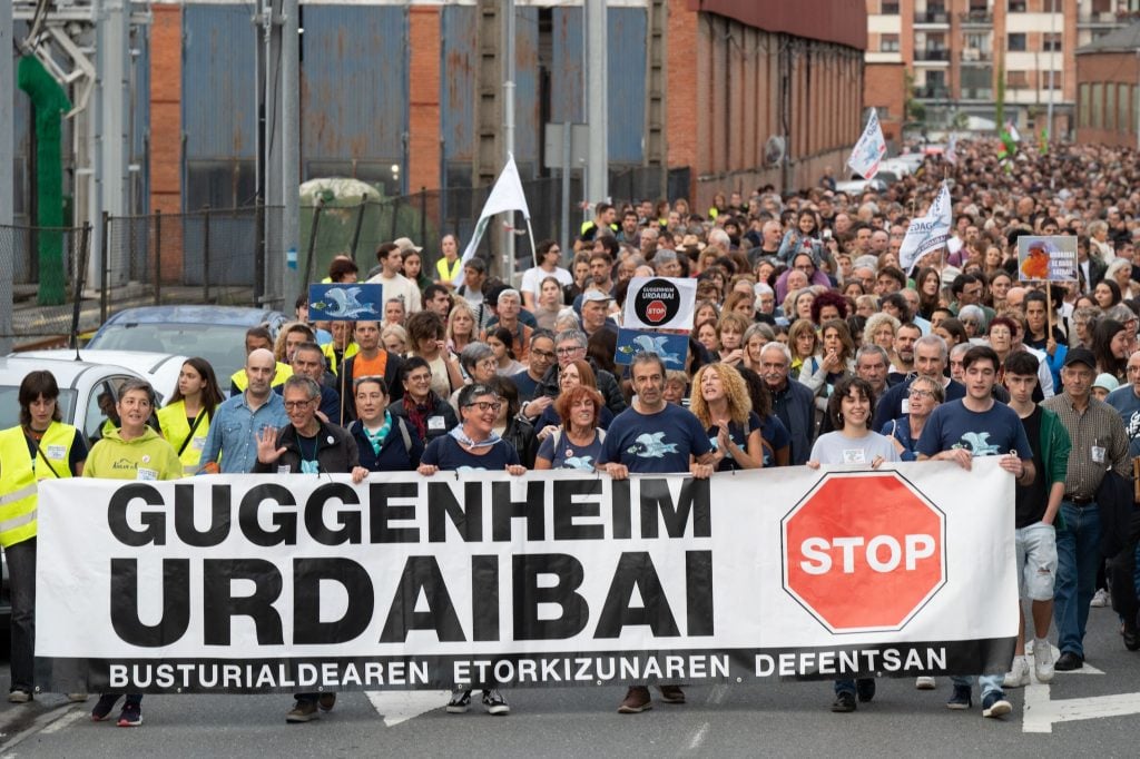 Marchers with signs indicating opposition to a Guggenheim outpost in Urdaibai, Spain