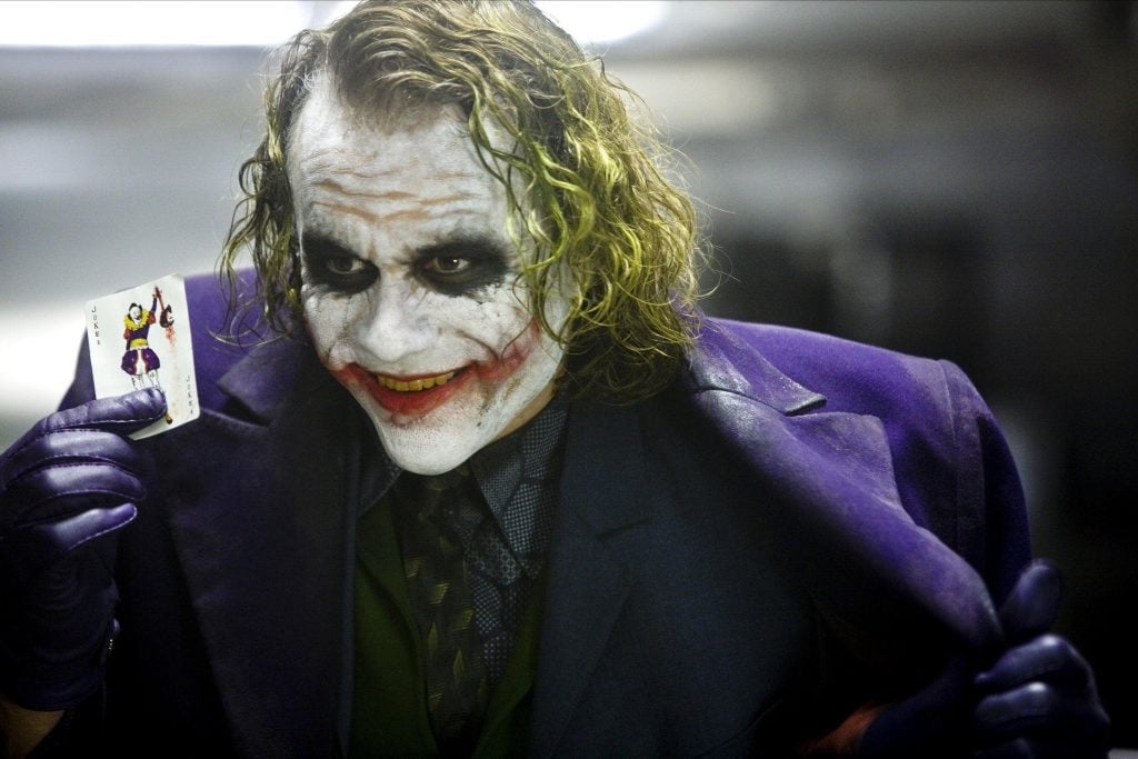 a photo of Heath Ledger as Joker with white makeup and red slash across the mouth