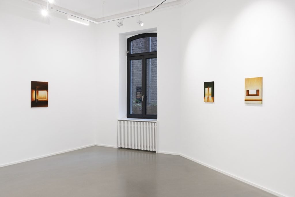 White gallery space with one window and three small-scale paintings installed on the walls by Szelit Cheung at Galerie Christian Lethert.