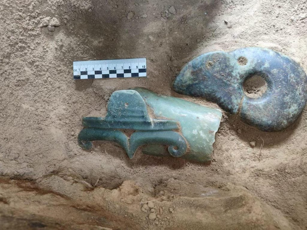 close up of two jade instruments on dirt background