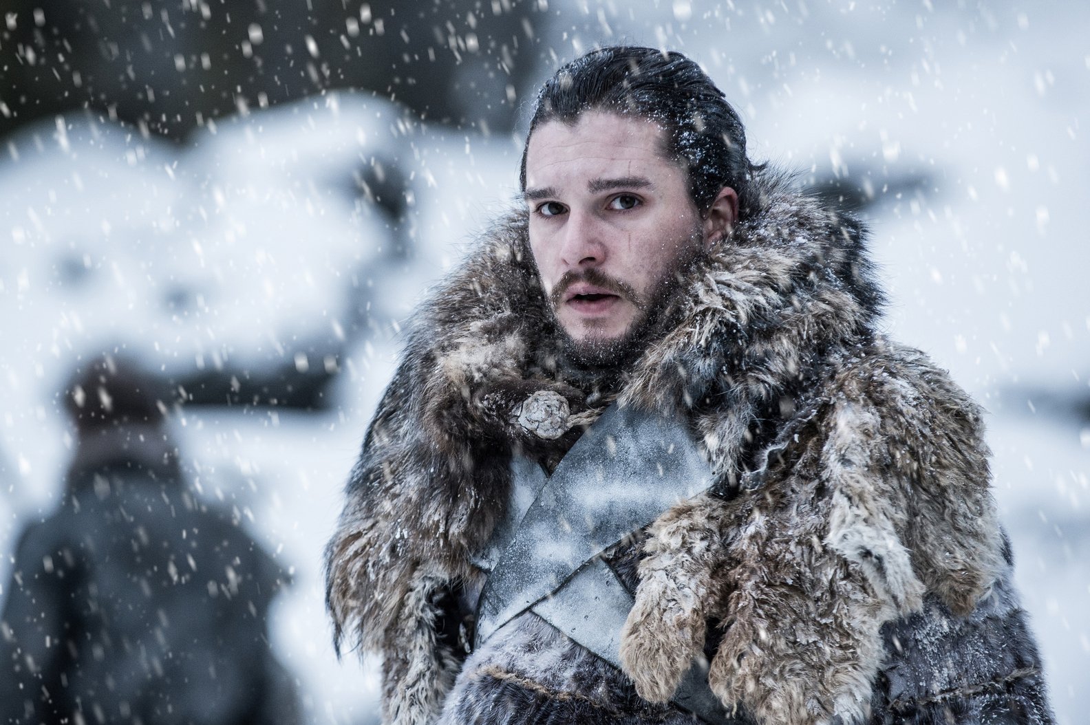 A bearded man wrapped in furs while standing in the snow