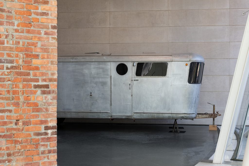 The exterior of a silver-colored mobile trailer in a museum lobby