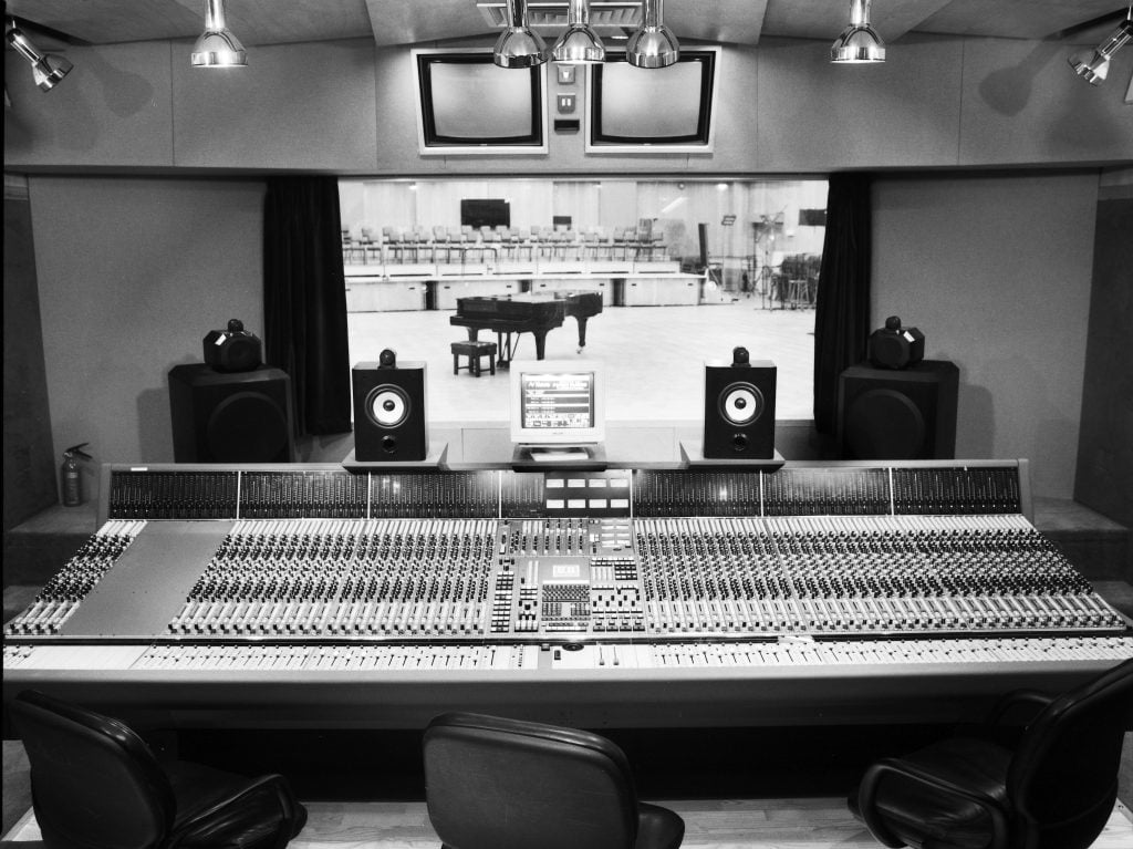 black and white photograph of a large recording console with many buttons inside a music recording studio