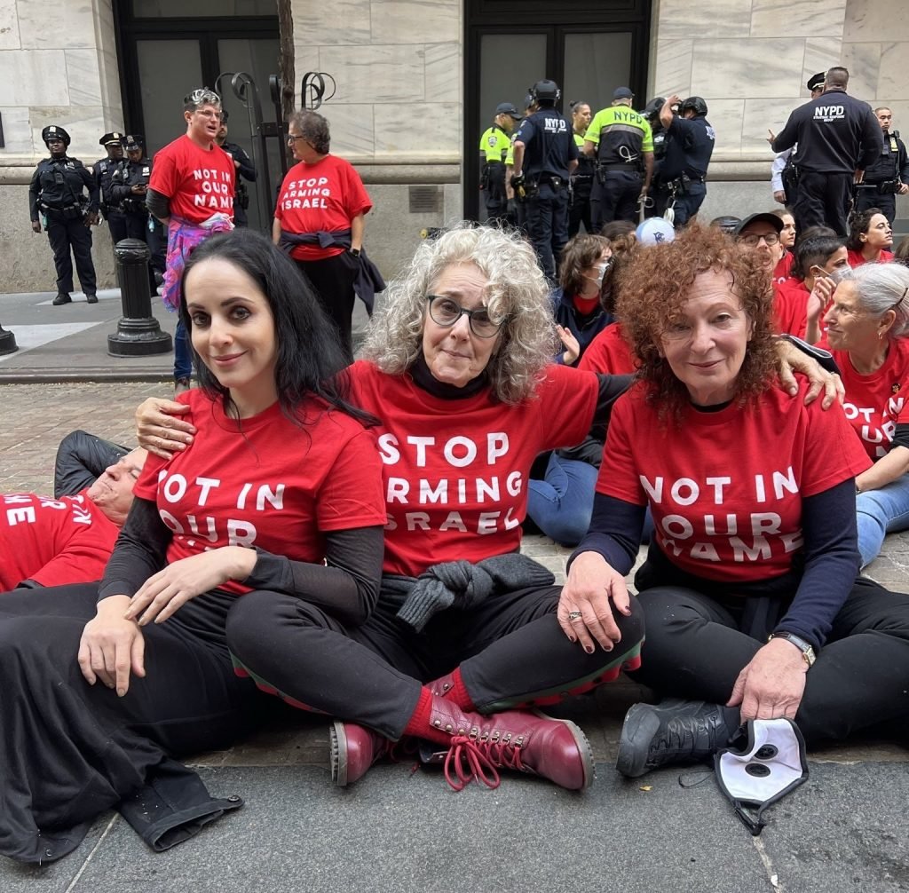 Three women in red shirts reading 