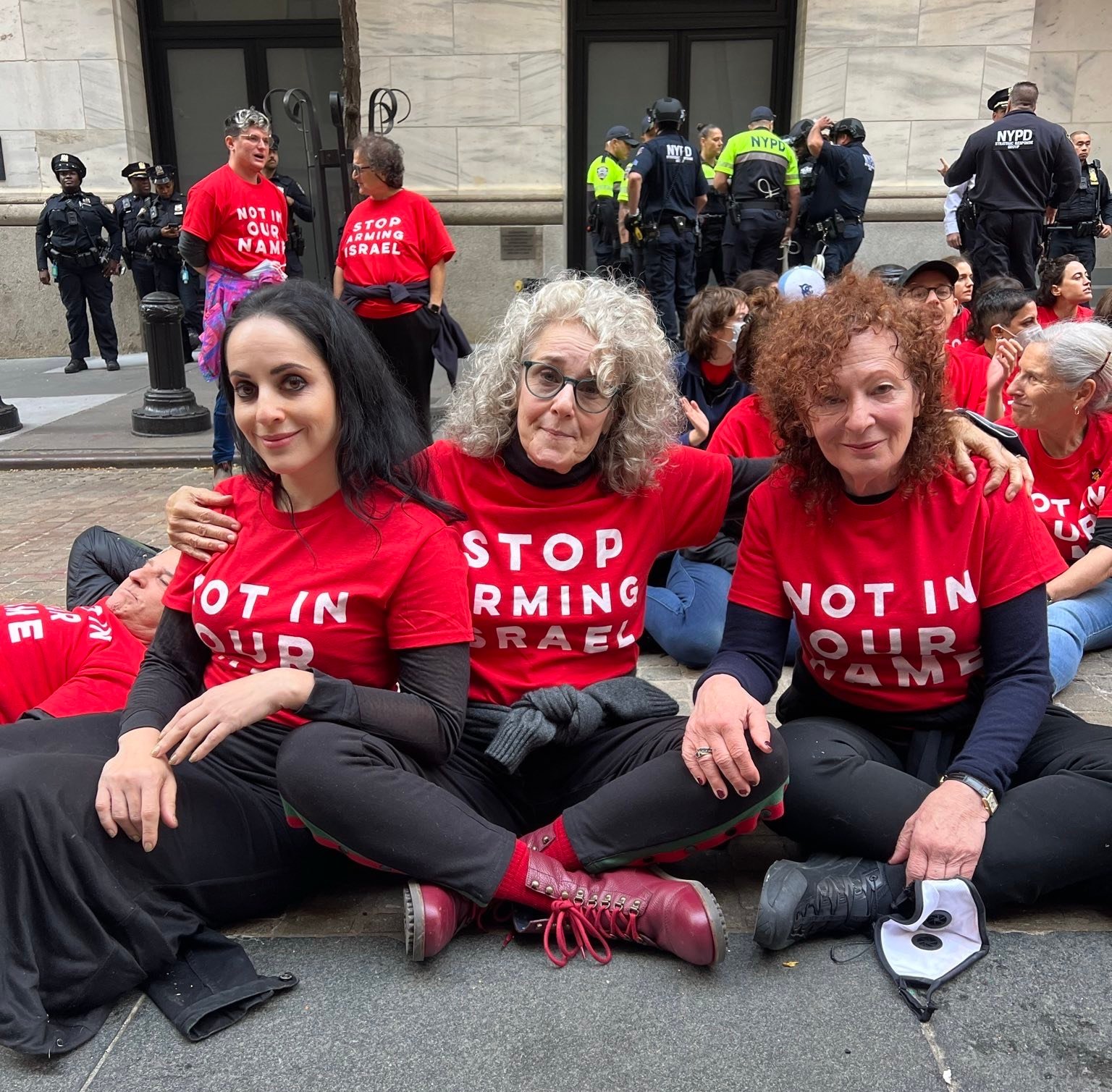 Three women in red shirts reading "not in our names" outside the New York Stock Exchange