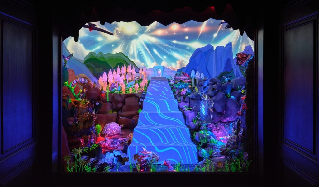 An otherworldly diorama lit with UV light, and populated with alien plants and sequin-studded sculptures of animals