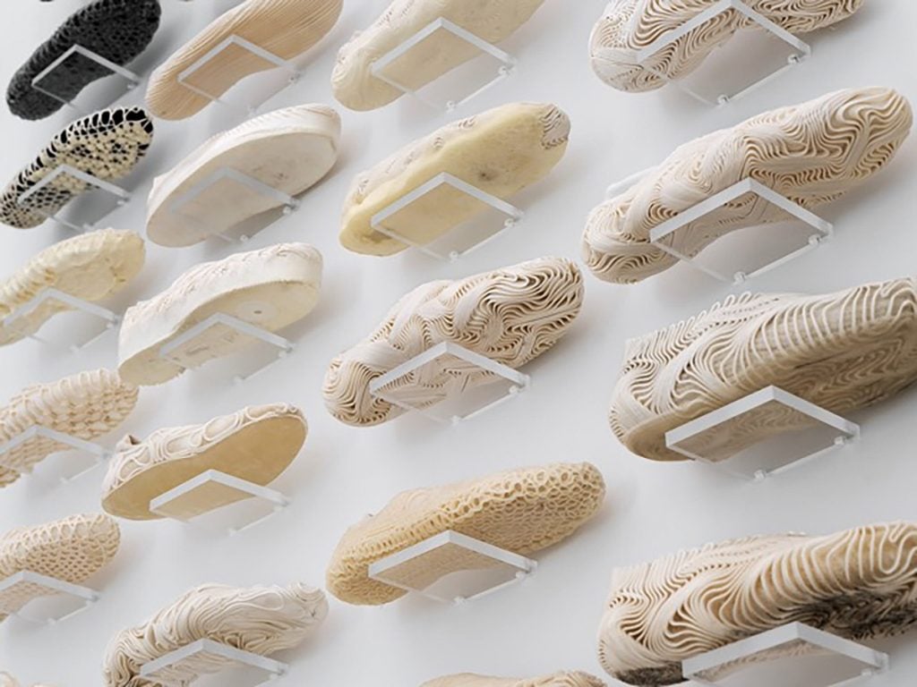 A wall displaying prototypes of shoes printed by a computer