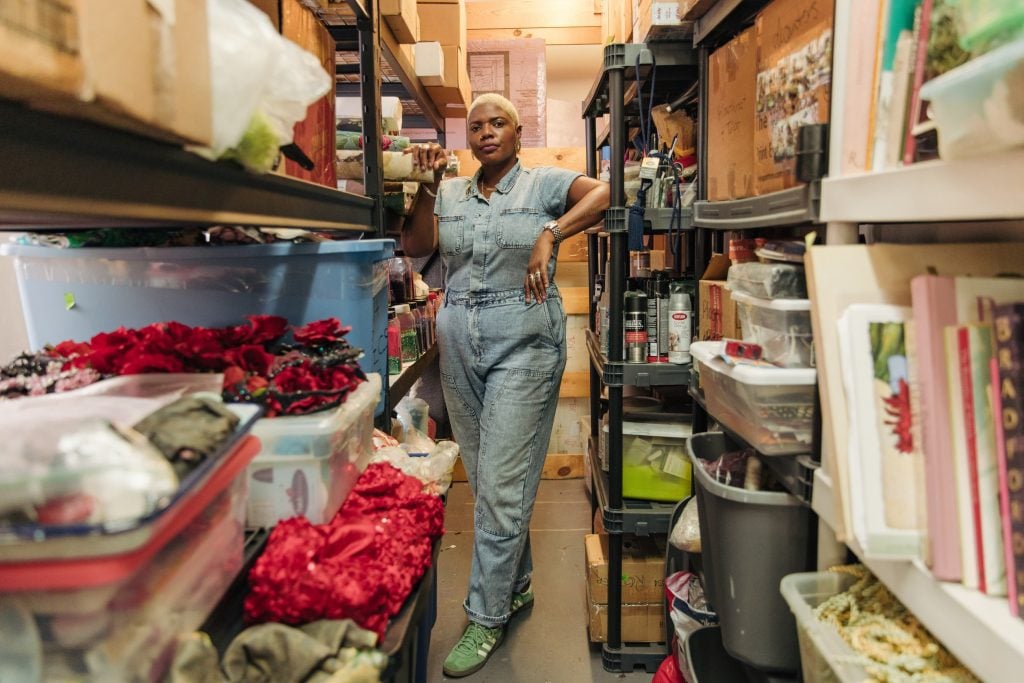 Artist Ebony G. Patterson in her studio amid storage shelves