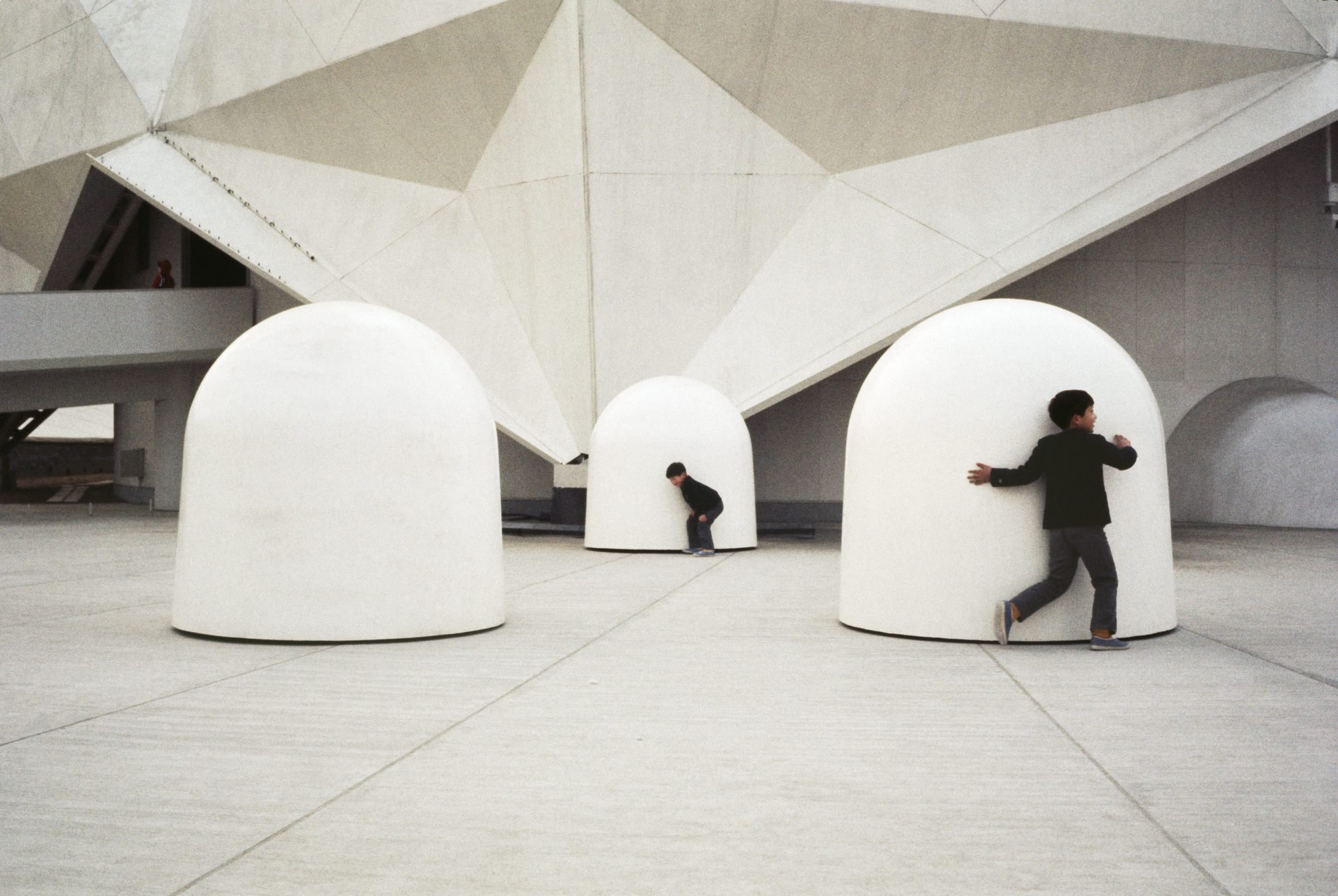 Two children playing around three white, dome-shaped structures