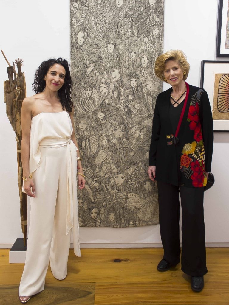 two women stand in front of an artwork in a gallery