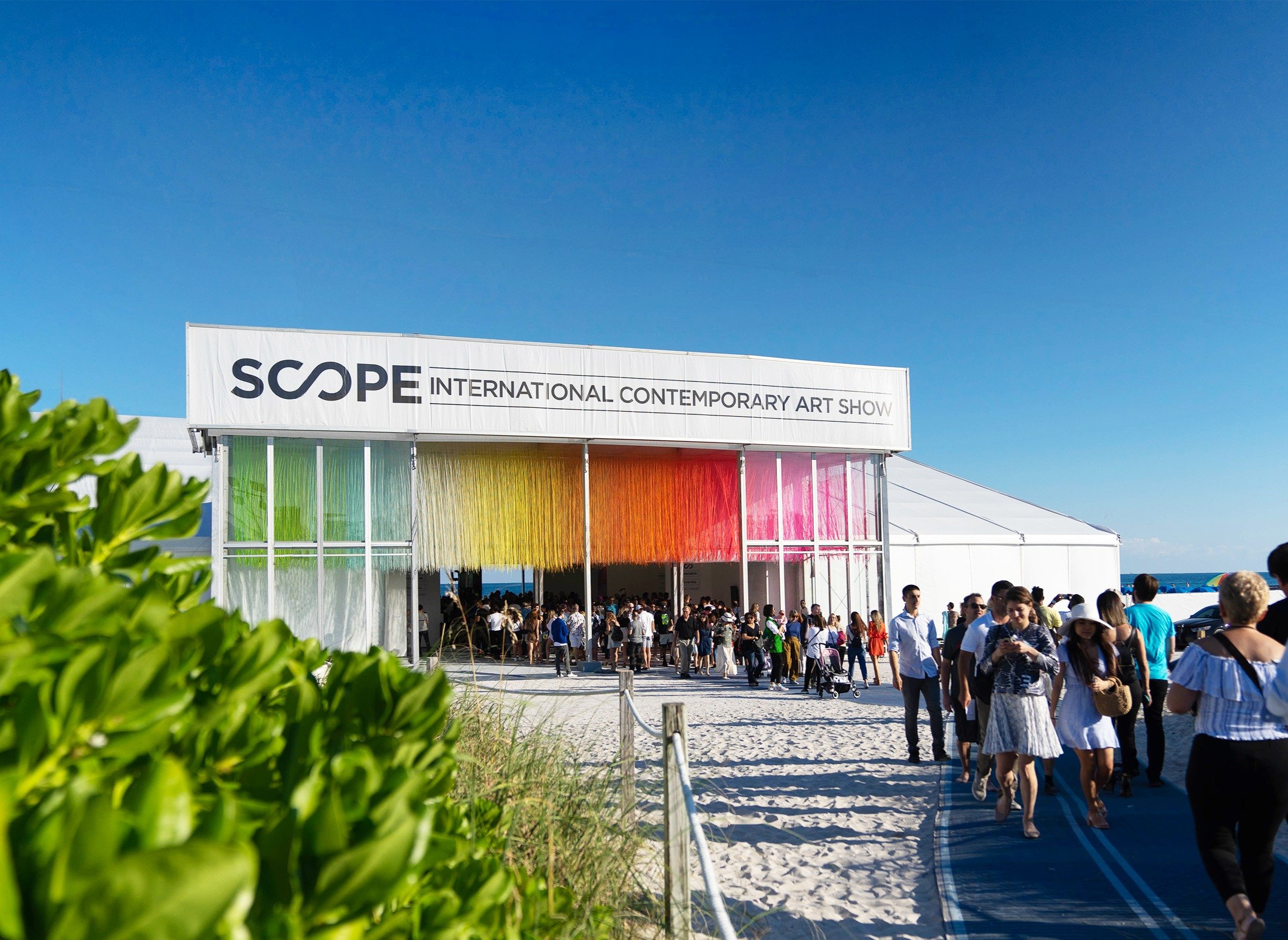 Exterior view of the Scope Art Show tent on Miami Beach 2023 with a rainbow installation across the front.