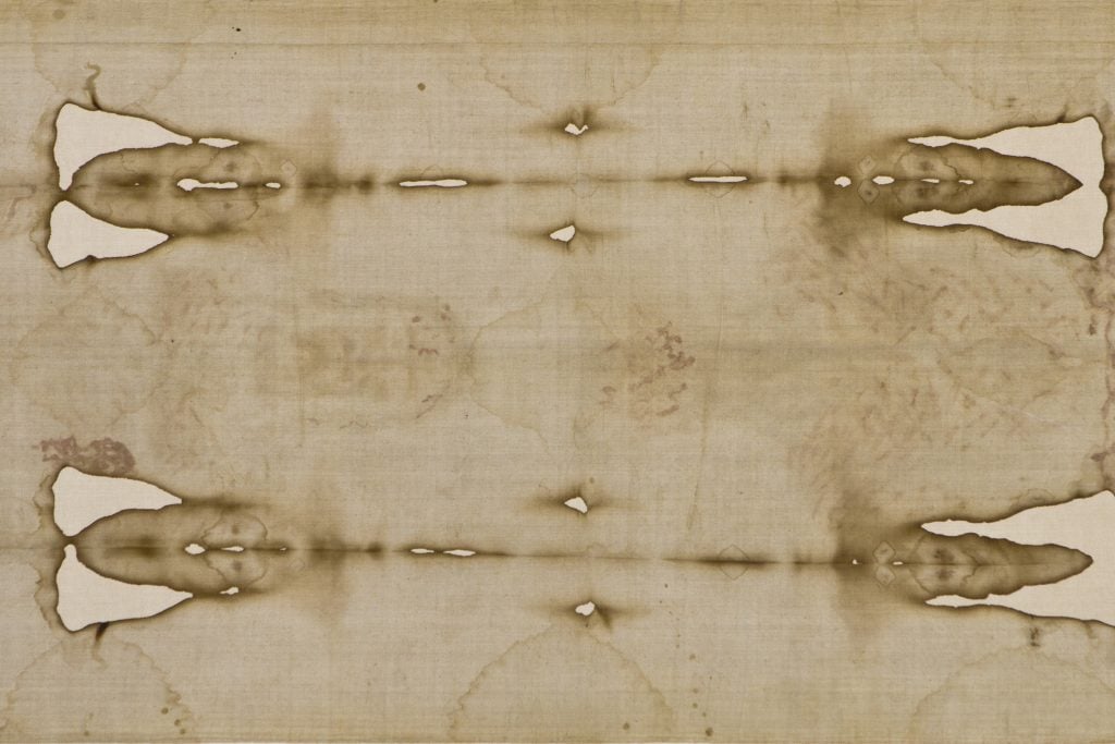 The Shroud of Turin, a piece of linen with rips and faint brown impressions