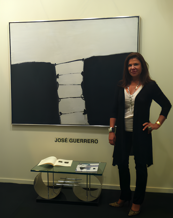 Portrait of Soraya Cartategui standing beside an abstract painting in white and black.