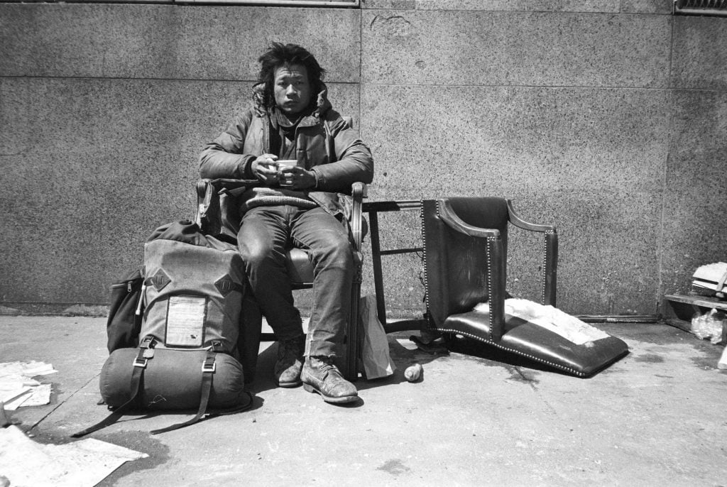 A Taiwanese man sits on a chair on the street.