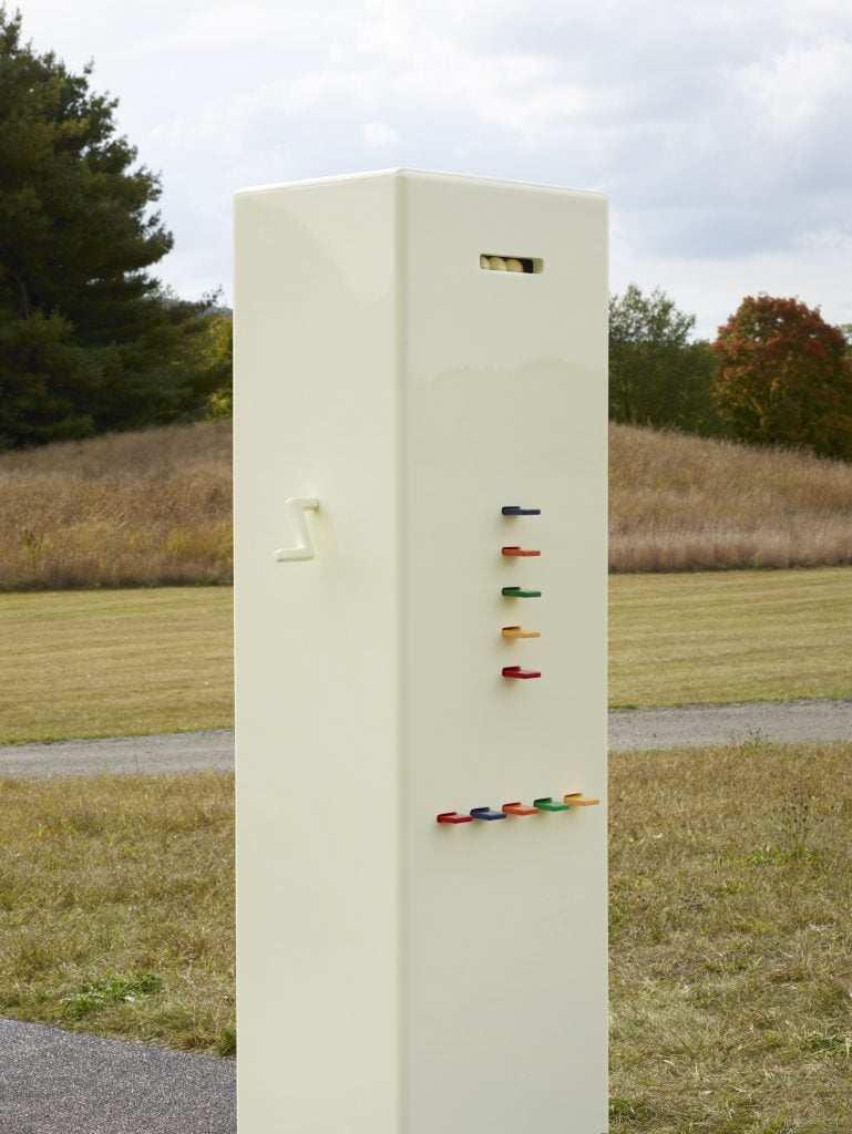 A close up of the Kleroterian machine by Taryn Simon Installed at Storm King Art Center, against a short lawn turning brown.