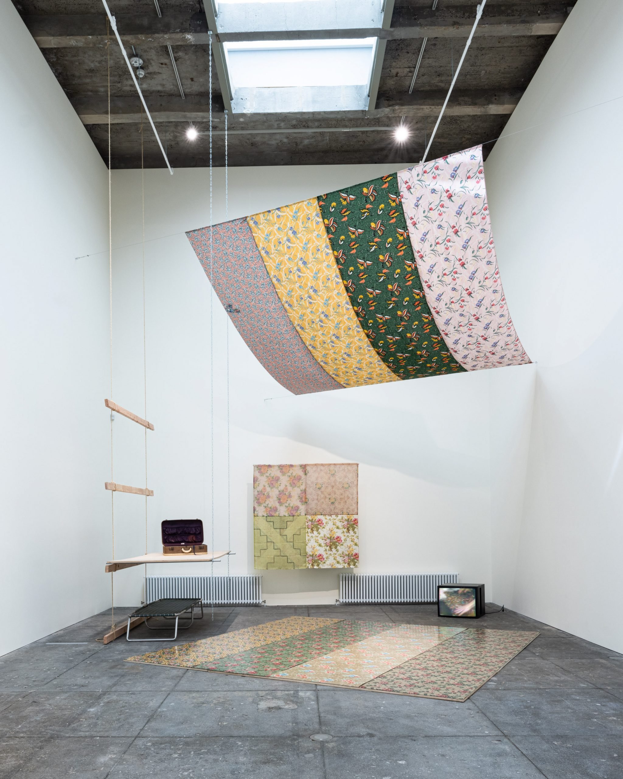 Installation view of "Tina Girouard: Sign In" at Center for Art Research and Alliances, New York. The hanging fabric sculpture is Air Space Stage. There are other works on the wall and floor.