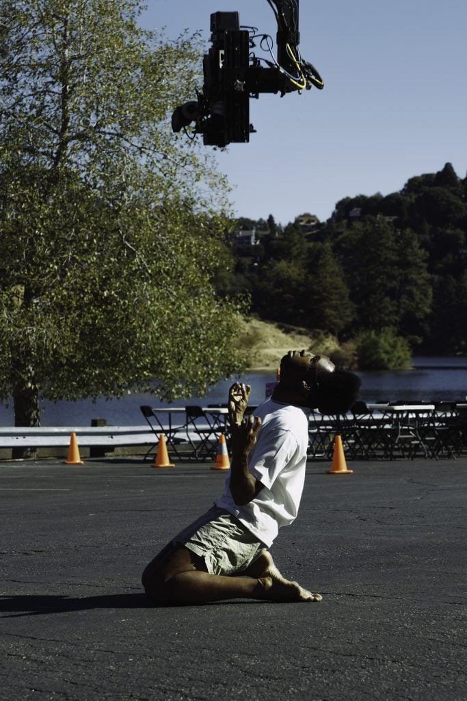 A man kneeling on the floor and yelling, while a camera points down at his face