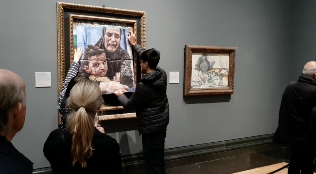 Monday-Malachi Rosenfeld and Jai Halai affixing a photo of a Gazan mother and her injured child over Pablo Picasso's 1901 painting Motherhood (La Maternité) at the National Gallery in London.