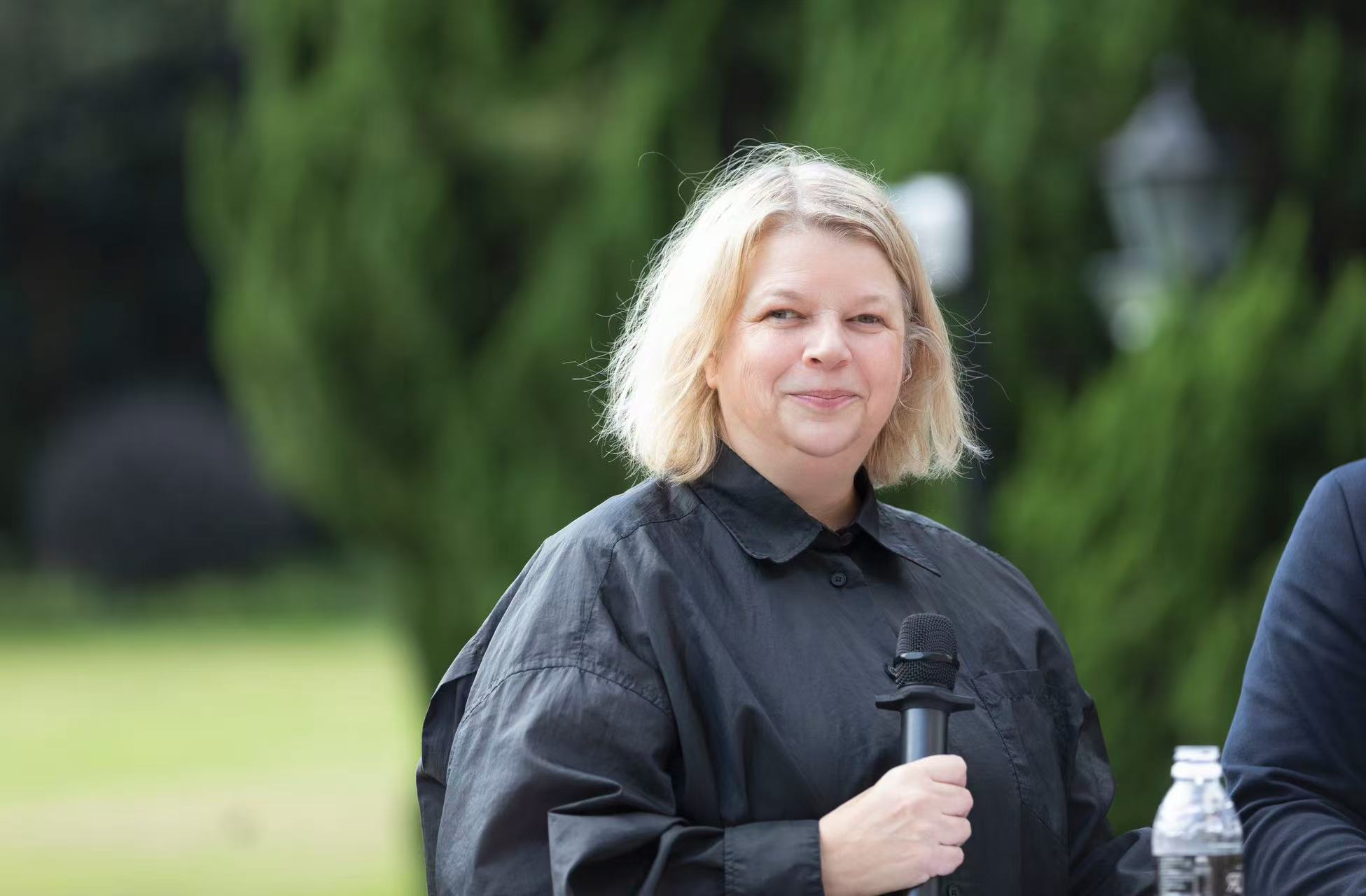 A woman in black holds a microphone