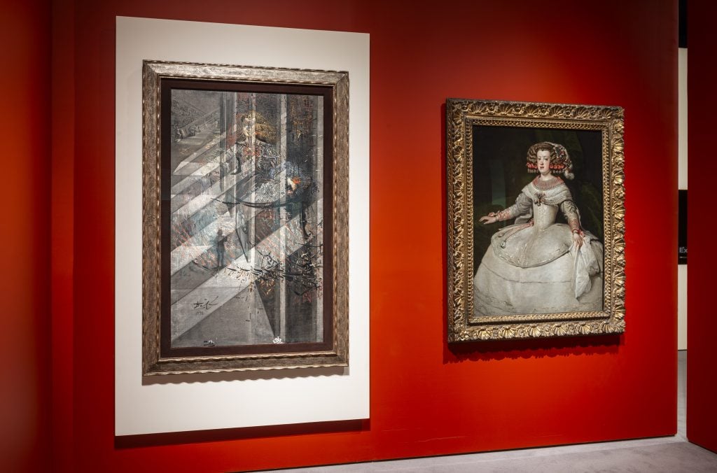 painting of a woman in a white dress with bare arms against a dark background inside a golden frame on a red wall next to another painting with a large white frame around it