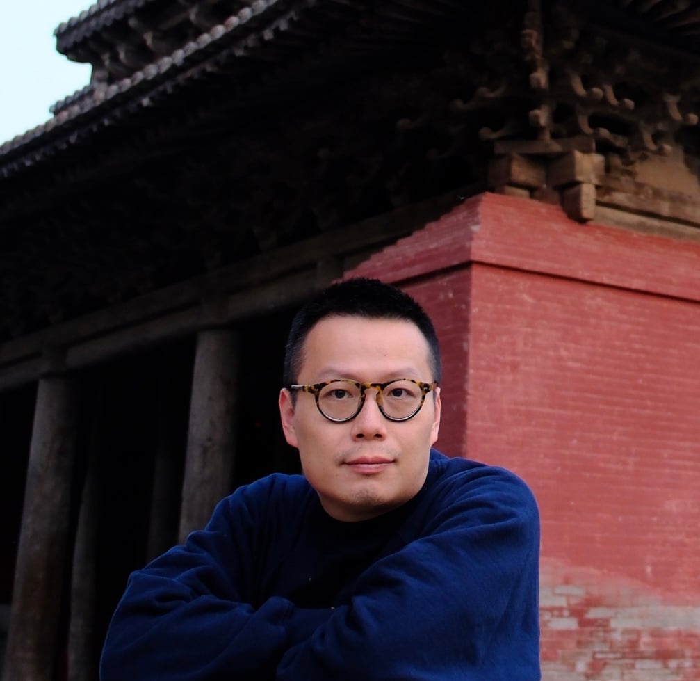 A man glasses poses in a color photo