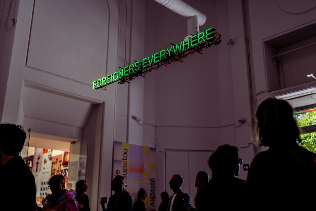 a sign is illuminated and says foreigners everywhere at a museum 