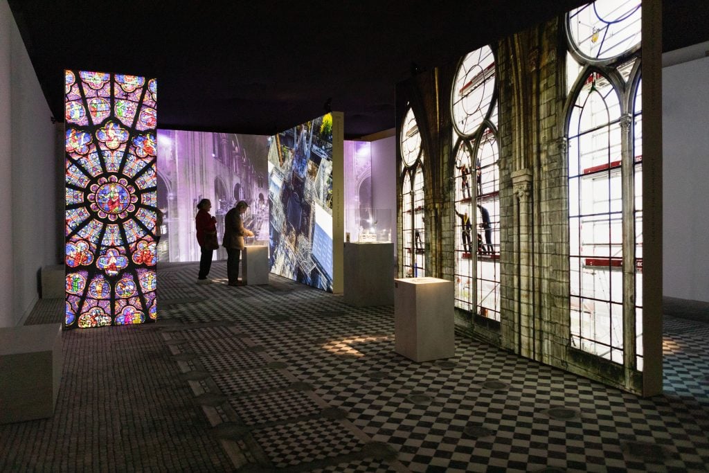 a scene from an exhibition with carpet floor looking like a cathedal and two people in the distance