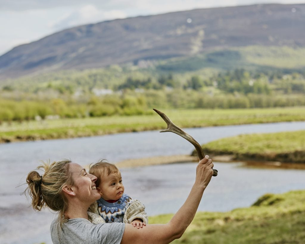 Smiling woman and child exploring nature near a river in the Scottish Highlands