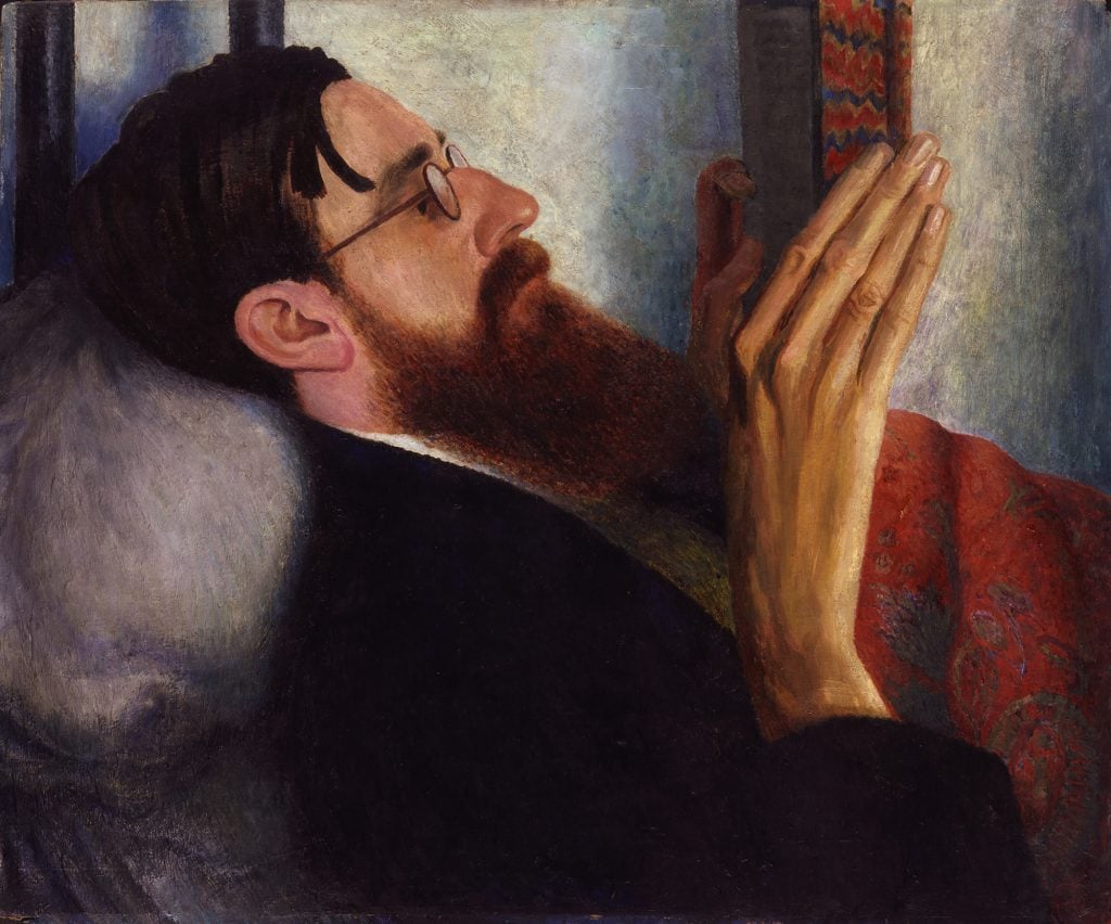 an image of a man with a beard lying down and reading a book