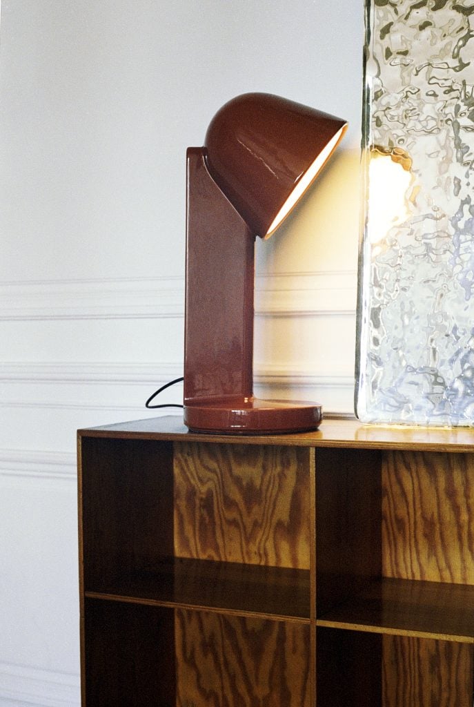 a red lamp is atop a wood shelf