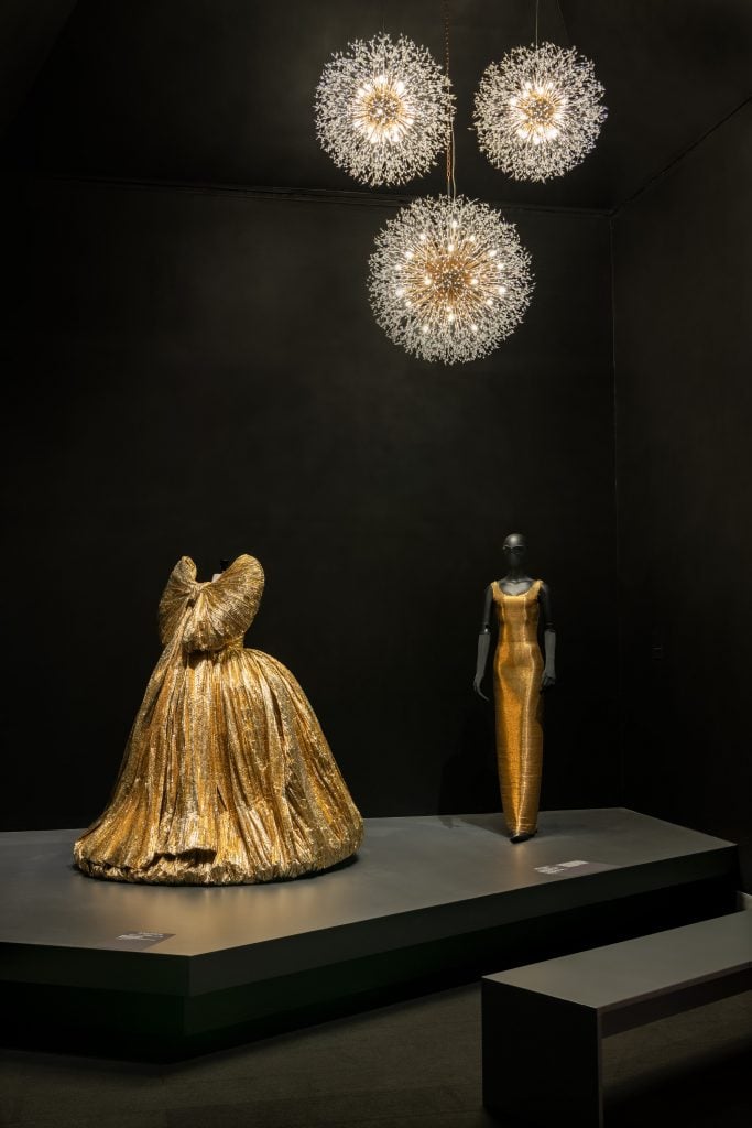 two golden dresses are in a museum exhibition 