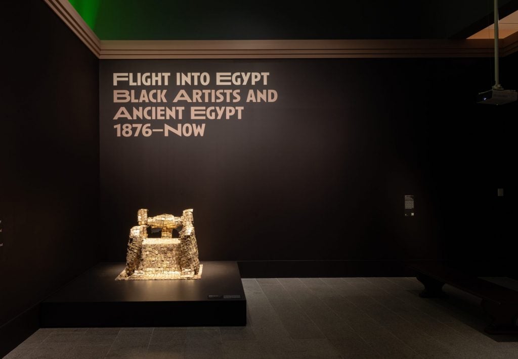 a golden throne sits in a museum gallery 