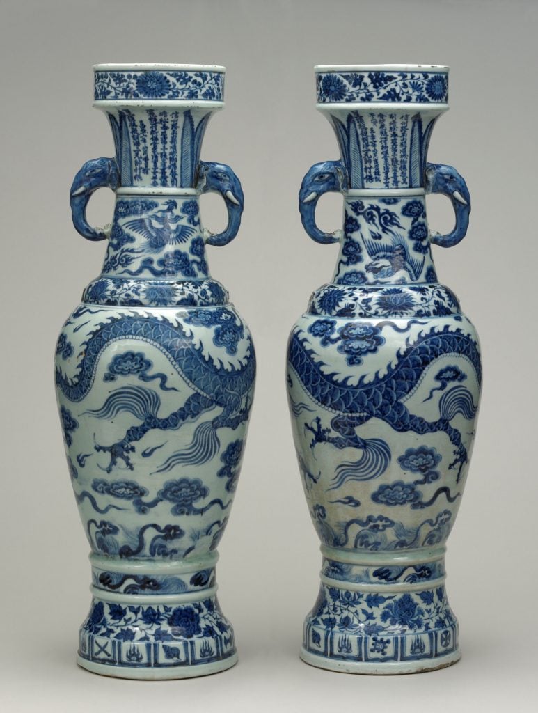 two blue and white ceramic vases covered in dragons and clouds and other decorative motifs