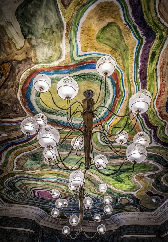 Stunning chandelier beneath a colorful, hand-painted ceiling resembling geological layers