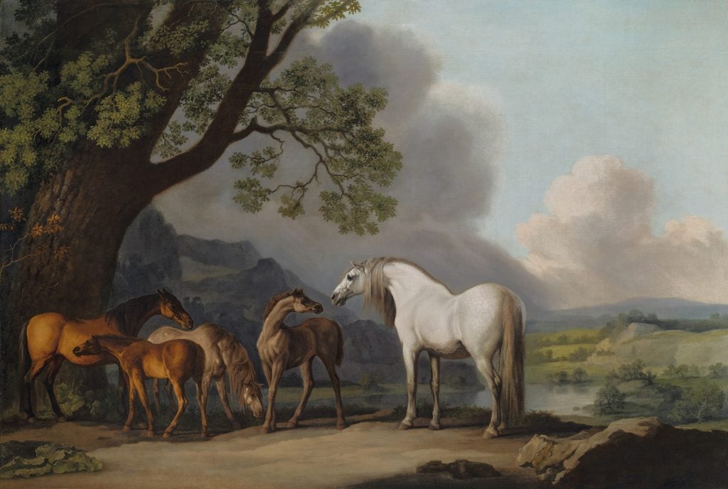 George Stubbs, Mares and Foals in an extensive landscape (1769). The painting is a landscape with four brown and gray foals beneath a tree on the left side, and their mother, a white mare, set against a cloudy sky with mountains, a lake, and green hills in the background. 