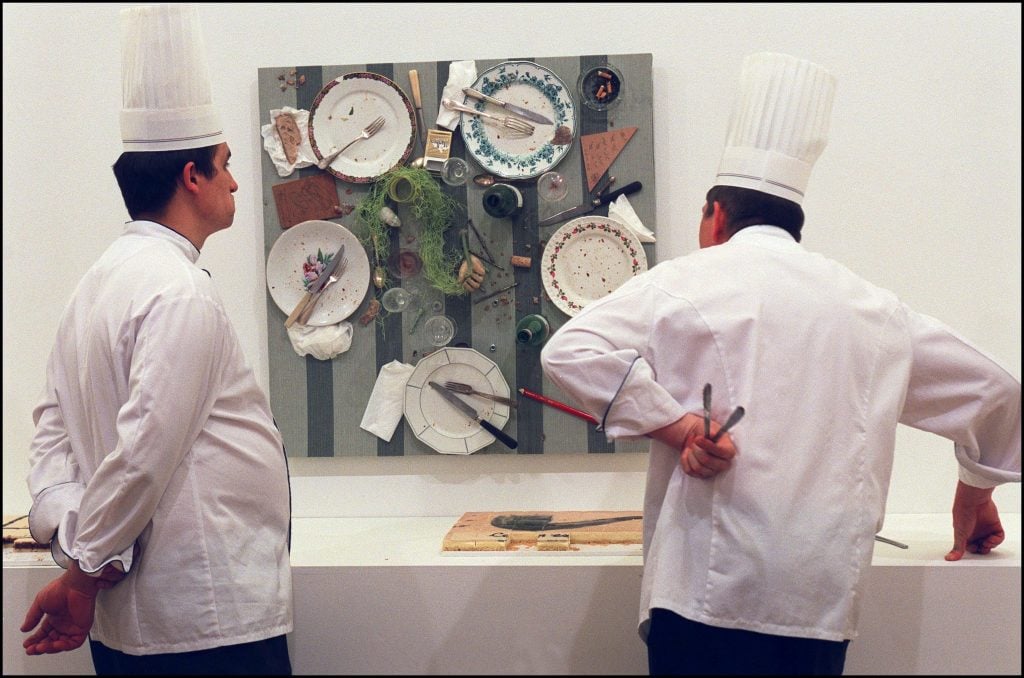 two chefs look at an artwork comprised of leftover meals