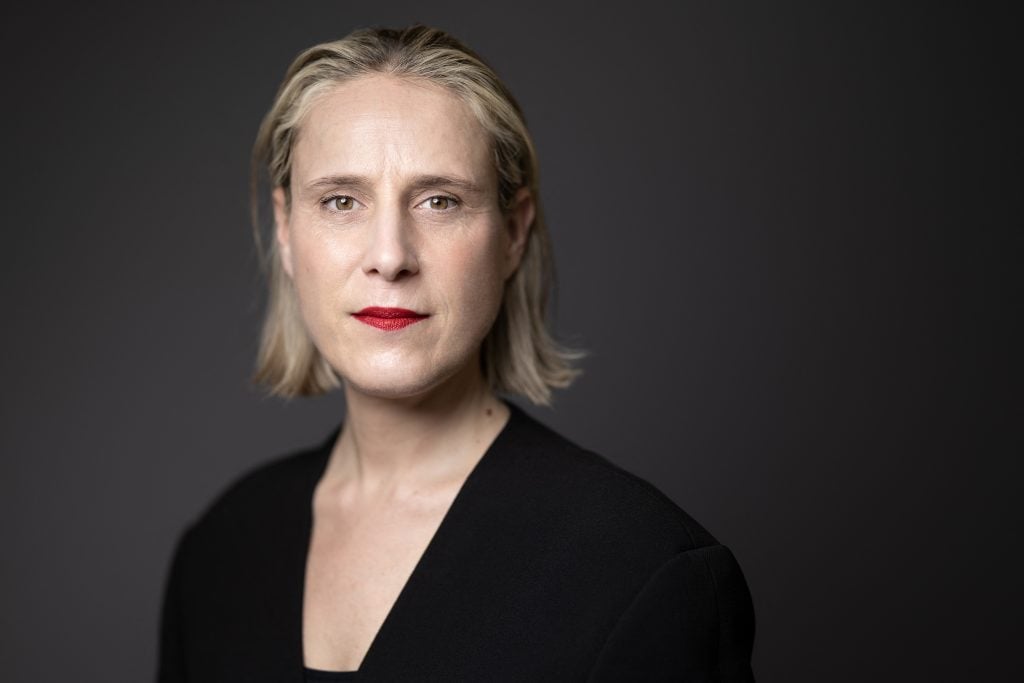 a portrait of a woman with chin-length blonde hair against a black backdrop