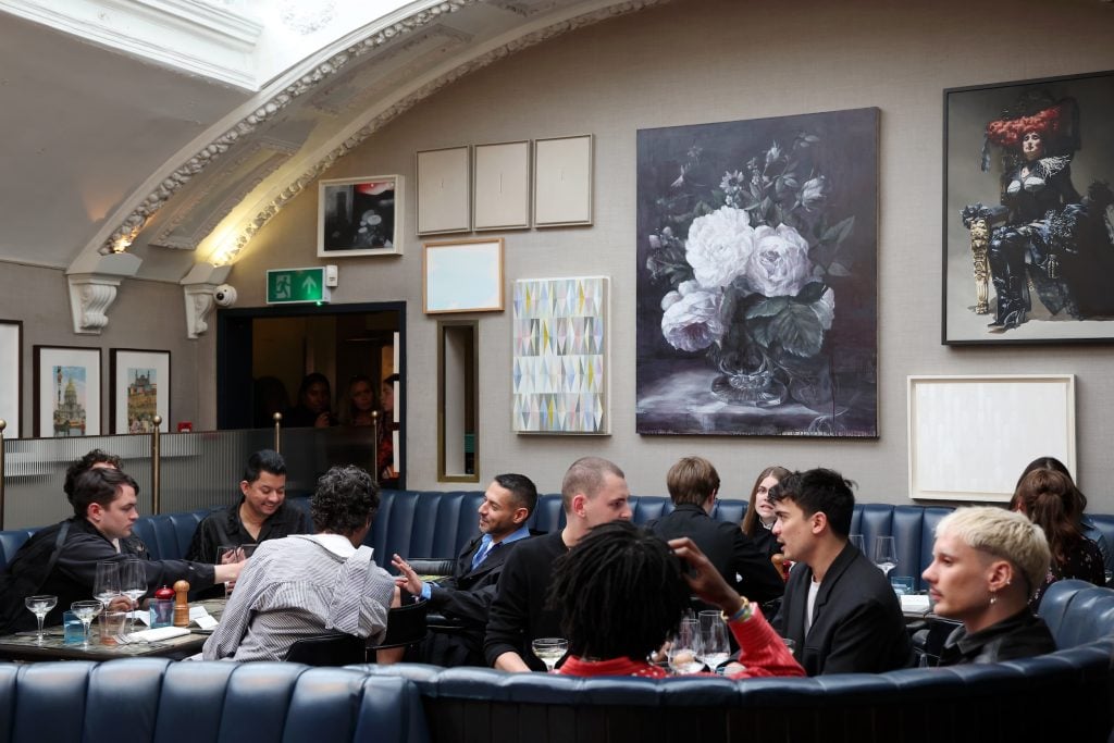 people are seen dining in a large room with natural light and lots of art on the walls