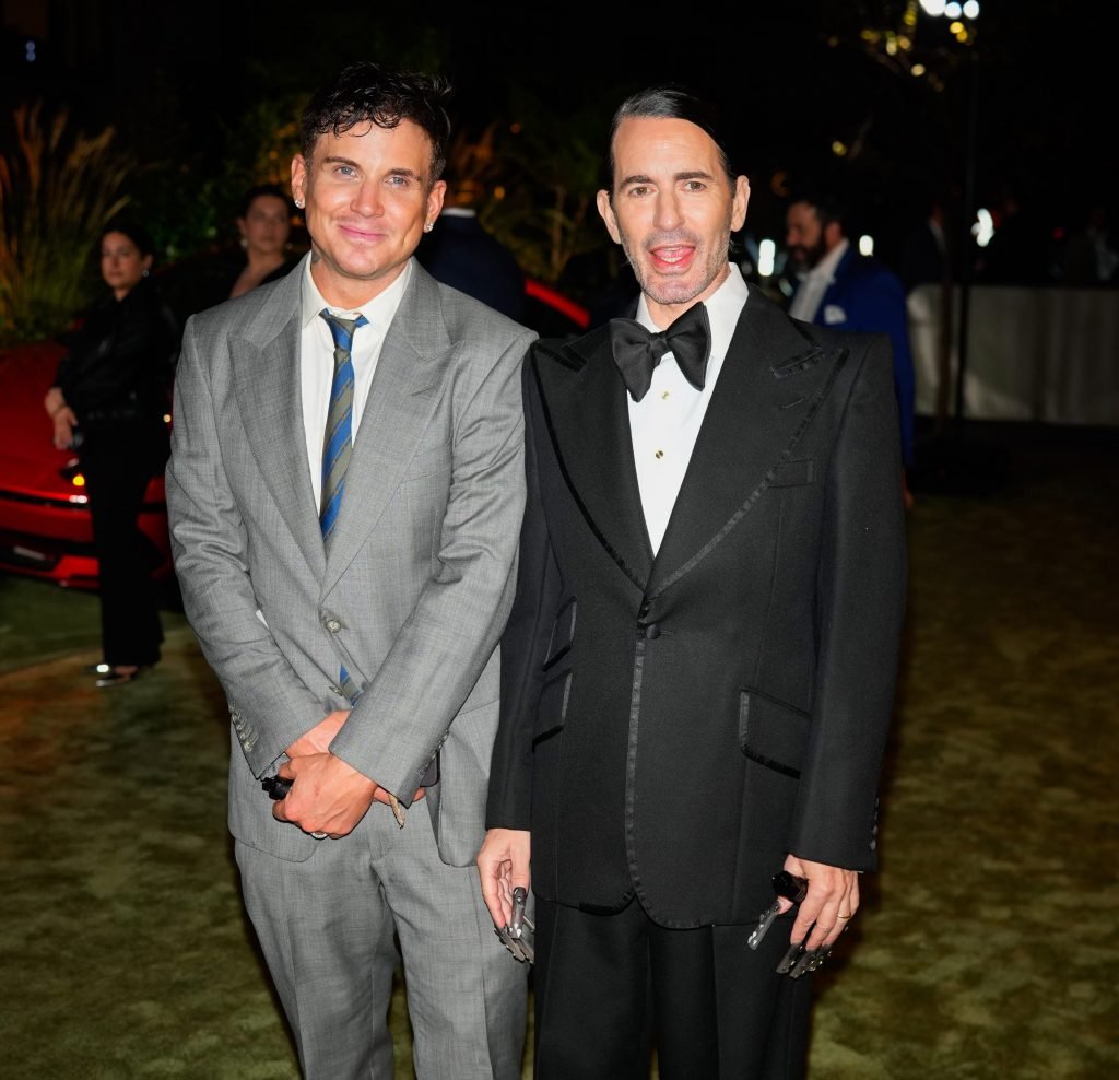 two men, one in a gray suit and one in a black tuxedo